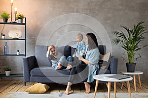 Young Mother Playing with Children on the Couch. happy family. home comfort.