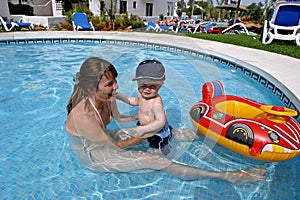 Mladý matka v dětské plavání bazén batole syn a nafukovací člun 