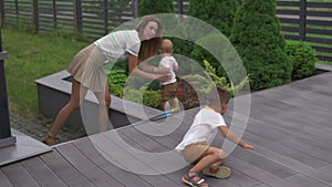 Young mother playing and having fun with her baby boy son brothers in a garden with toys - Family values warm color