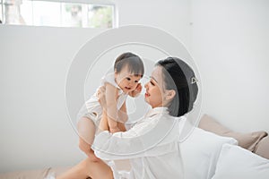 Young mother playing with her baby in bedroom at home