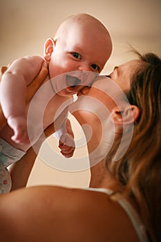 Young mother playing with her baby boy in bed.