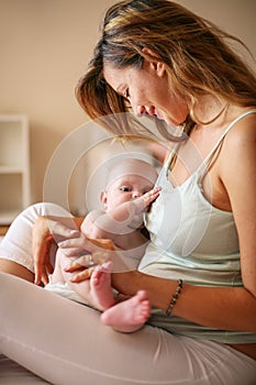 Young mother playing with her baby boy in bed.