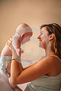 Young mother playing with her baby boy in bed.