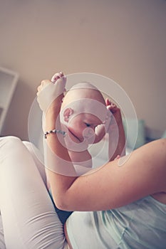 Young mother playing with her baby boy in bed.