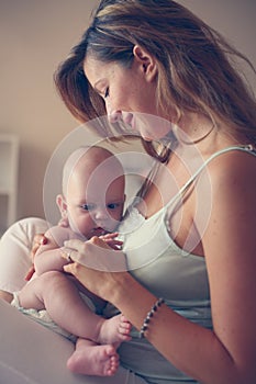 Young mother playing with her baby boy in bed. Mother enjoying