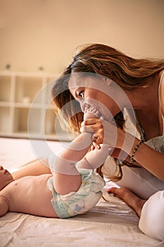 Young mother playing with her baby girl in bed.