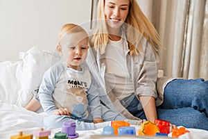 Young mother playing with her baby son at home