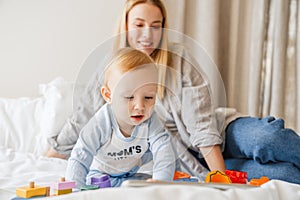 Young mother playing with her baby son at home