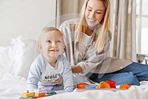 Young mother playing with her baby son at home