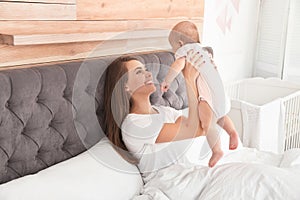 Young mother playing with her cute baby on bed