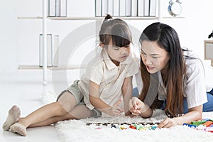 Young mother playing with her daughter in morning in bedroom. Mother and her child girl playing and hugging.