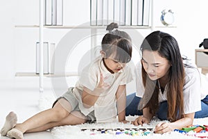 Young mother playing with her daughter in morning in bedroom. Mother and her child girl playing and hugging.