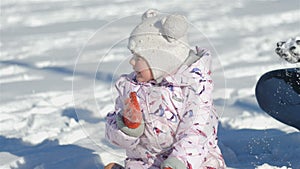 A young mother is playing with her daughter in the old park in the snow, the girl is enthusiastically happy with the