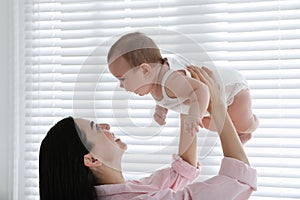 Young mother playing with her little baby at home