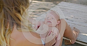 a young mother plays with a 3 month old baby holding it on the arms, the child smiles at his mother, the baby learns the