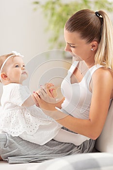 Young mother plays with a baby girl on her lap