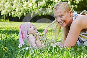 Young mother plays with baby on grass