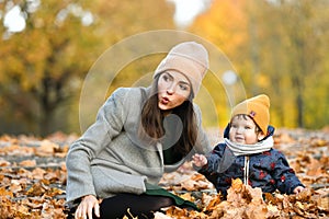 Young mother plays with a small child in an autumn park
