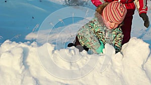 Young mother plays in a snow drift with her child