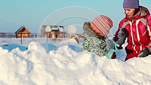 Young mother plays in a snow drift with her child