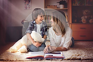 Young mother, read a book to her child, boy in the living room o