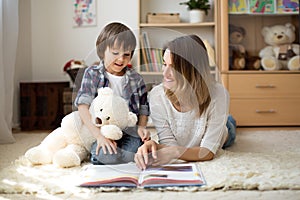 Young mother, read a book to her child, boy in the living room o photo