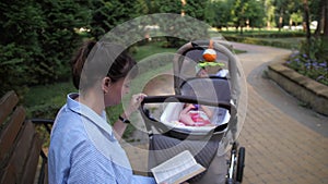 Young mother reading a book with baby in stroller