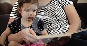 A young mother reading a book with her toddler.