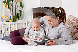 Young mother, reading a book to her baby boy, showing him pictur