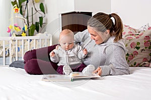 Young mother, reading a book to her baby boy, showing him pictur