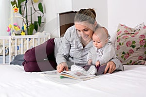 Young mother, reading a book to her baby boy, showing him pictur