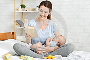 Young mother reading book to her newborn baby