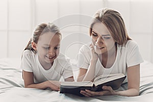 Young Mother Reading Book to Little Daughter