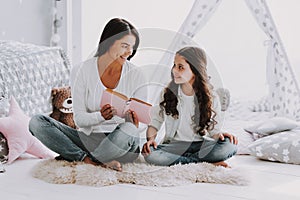 Young Mother Reading Book to Little Daughter