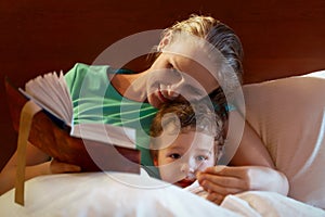 Young mother reading to her child in bed