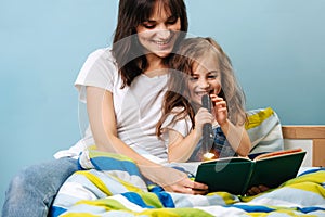 Young mother reads her daughter a book before going to bed