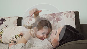 Young mother relax on sofa with little daughter