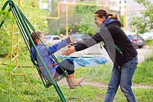 Young Mother Riding Little Daughter on Seesaw in Spring Park