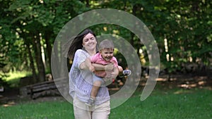 Young mother runs in the park with her son in her arms