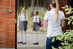 Young mother seeing of her children to school and waving to them