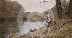 Young mother is showing to her little son lake and forest, walking at nature at autumn day, happy motherhood and