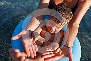 A young mother shows the legs and arms of her baby, who is sitting in an inflatable ring in the sea