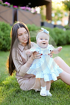 Young mother sitting on grass with little daughter.