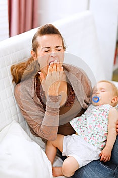 Young mother with sleeping baby on hands yawing photo