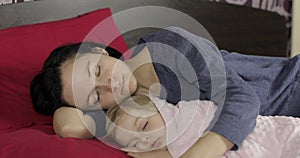 Young mother sleeping with her little baby daughter. Family sleeping on the bed