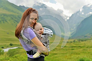 Young mother with a small child in a backpack-carrying travels in the mountains