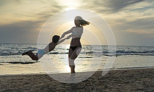 Young mother and smiling baby boy son playing on the beach on the Sunset. Positive human emotions, feelings, joy. Funny cute child