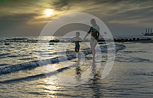 Young mother and smiling baby boy son playing on the beach on the Sunset. Positive human emotions, feelings, joy. Funny cute child