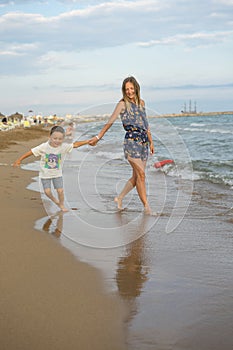 Young mother and smiling baby boy son playing on the beach on the Sunset. Positive human emotions, feelings, joy. Funny cute child