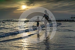 Young mother and smiling baby boy son playing on the beach on the Sunset. Positive human emotions, feelings, joy. Funny cute child